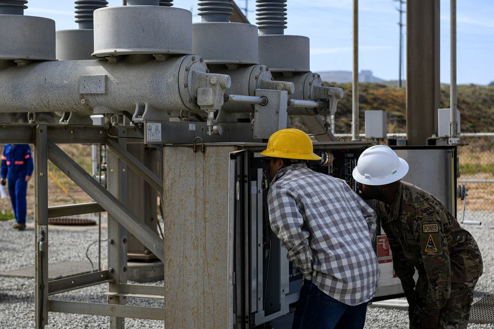 Engineers working on high-voltage electrical equipment at a substation
