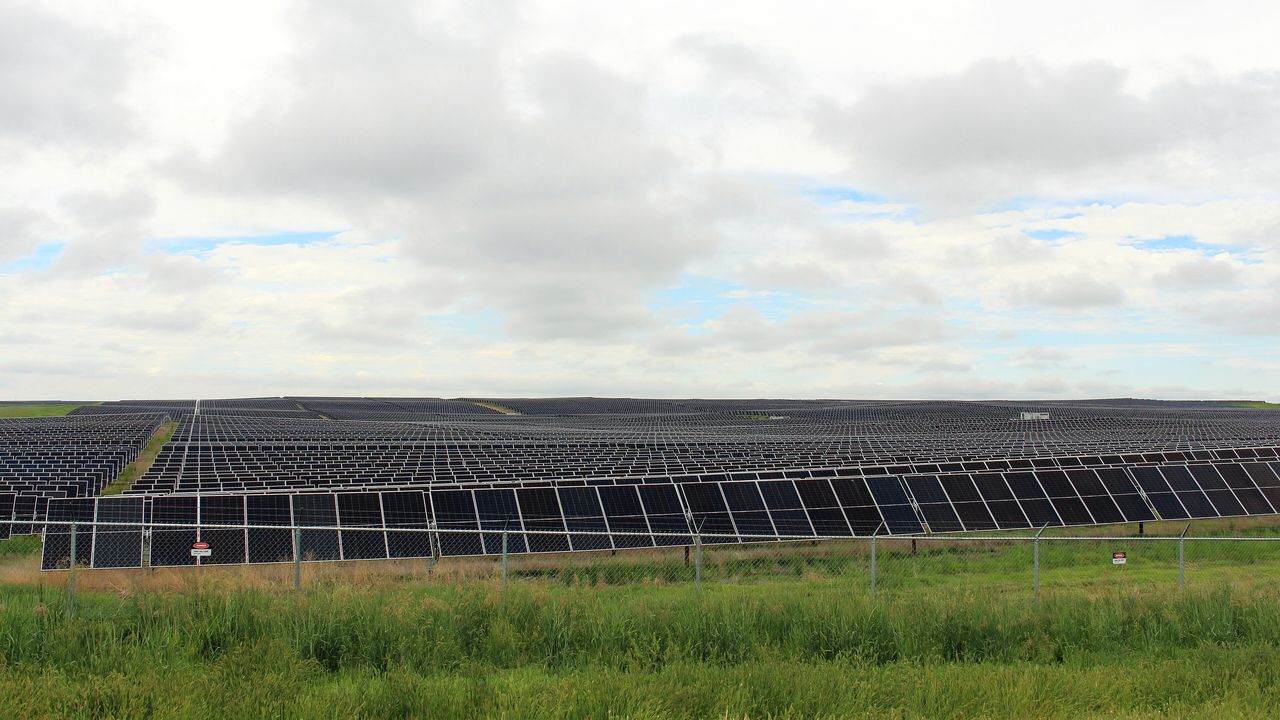 A utility-scale solar field under a broken sky