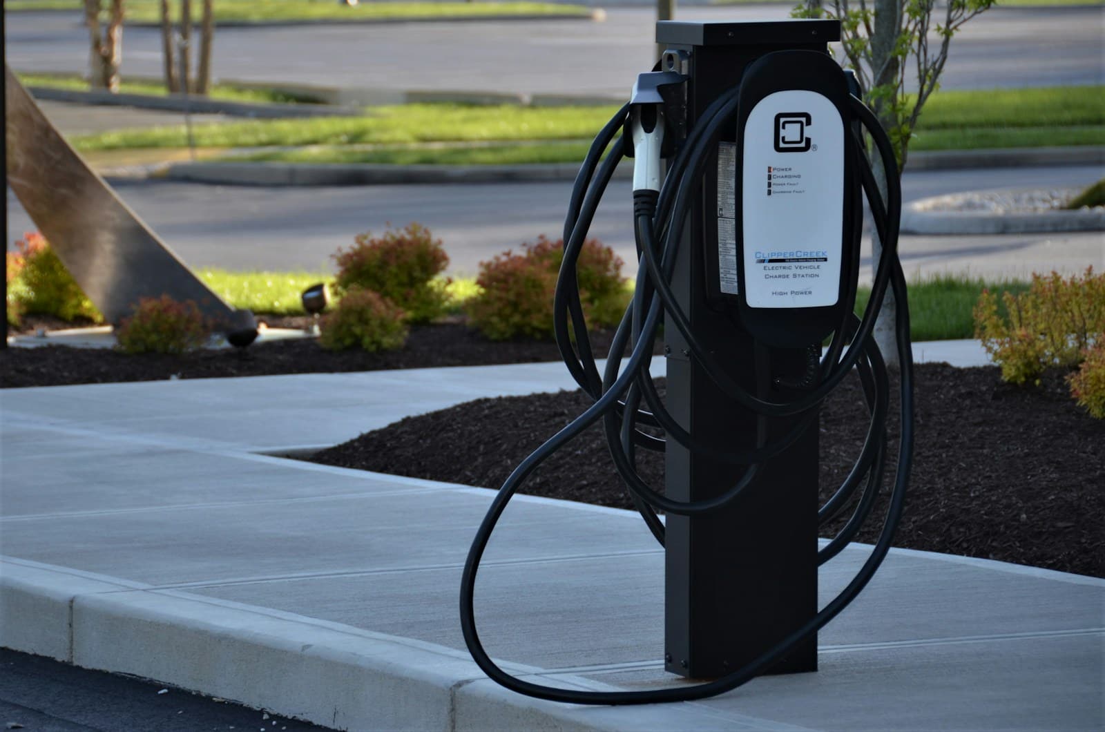 Free-standing charging post on a landscaped kerb in daylight