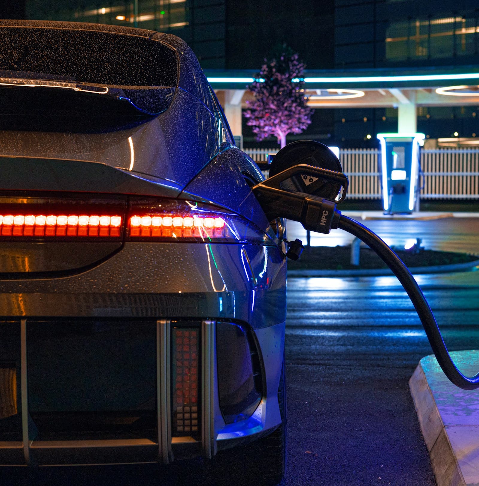 Rear of an electric car with the charging cable connected after dark