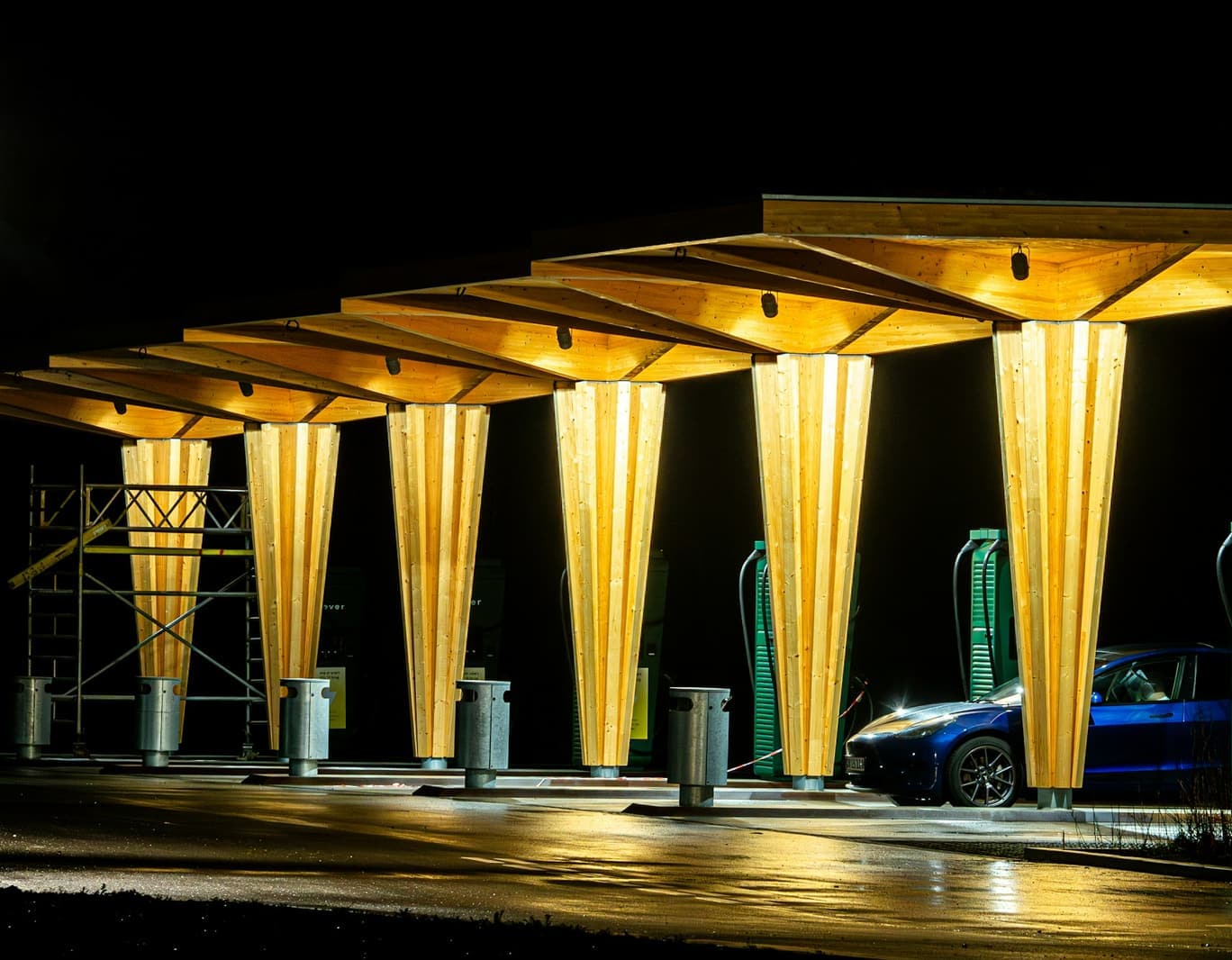 Timber-canopied highway charging forecourt lit at night
